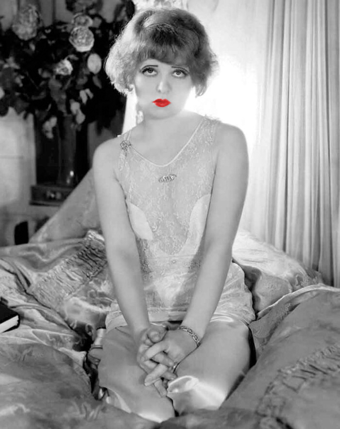 Clara Bow® sitting on the bed in lingerie with red lips